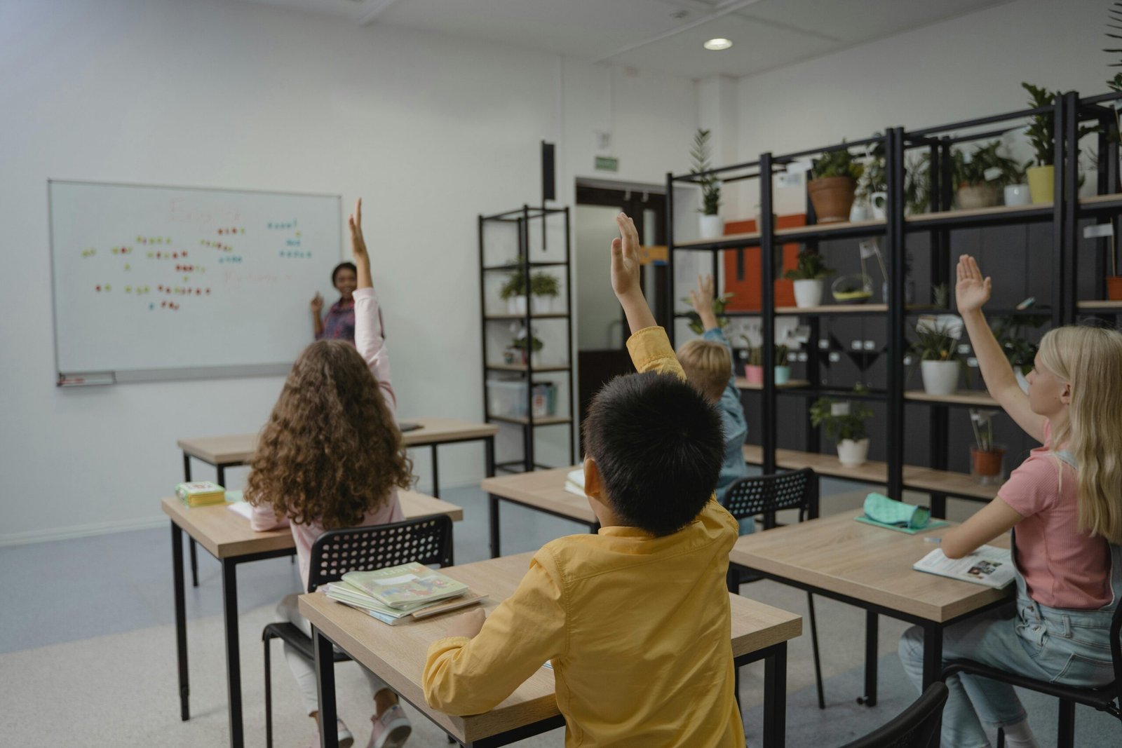 Students learning in a classroom with their hands up